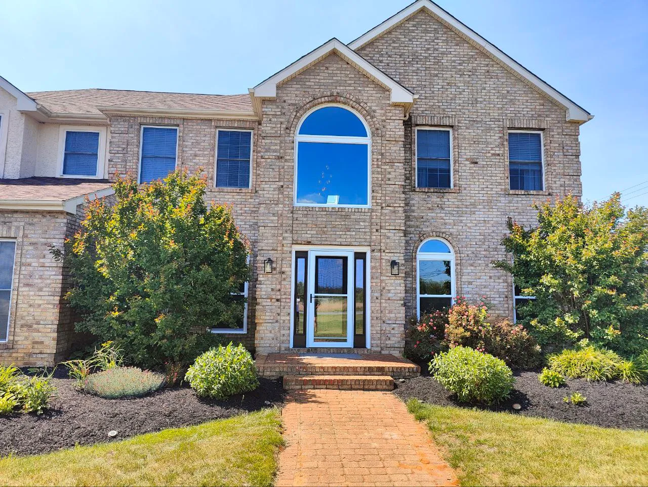 Brick home entry with a grand arched picture window above the front door