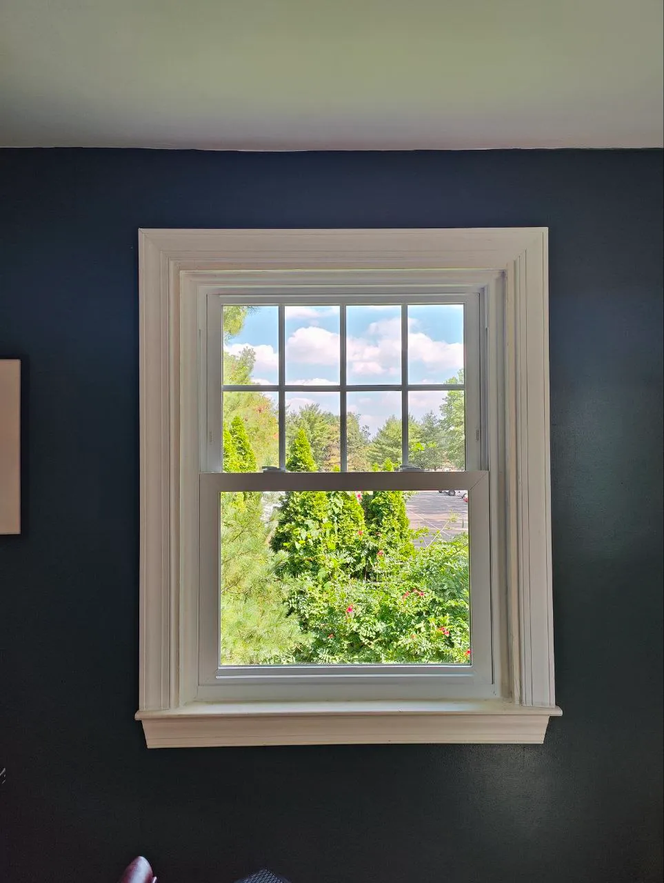 New white double-hung window with grilles set against a deep navy wall
