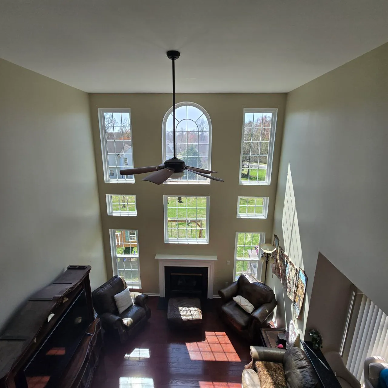 Sun-flooded two-story living room with a full wall of new windows topped by an arched unit